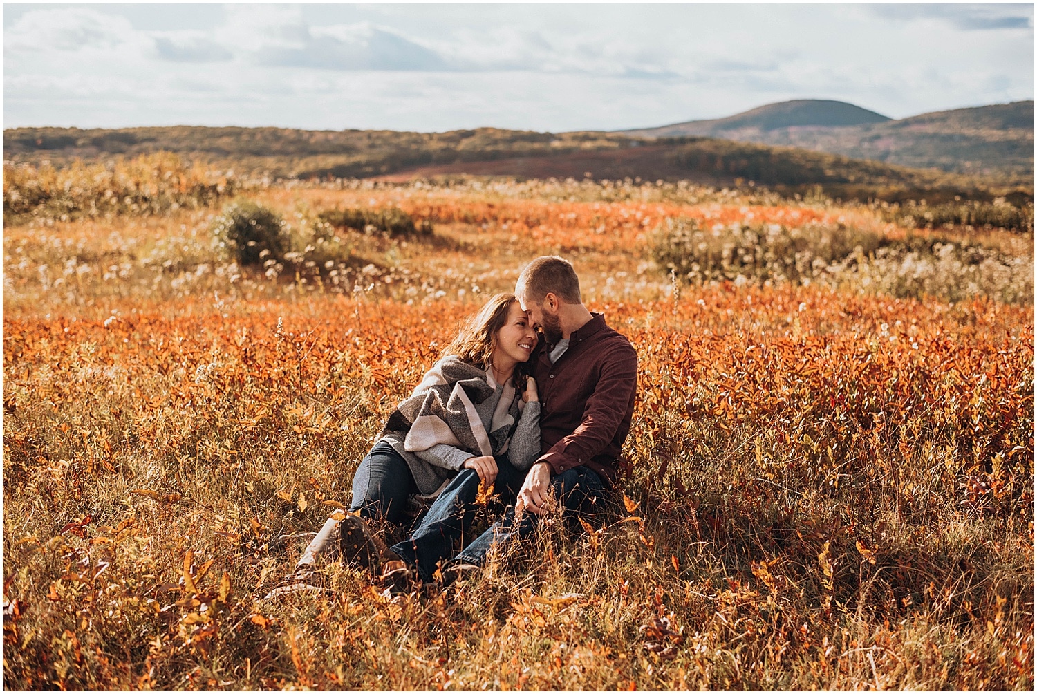 couple sitting in a field at their Rockland Maine Engagement session