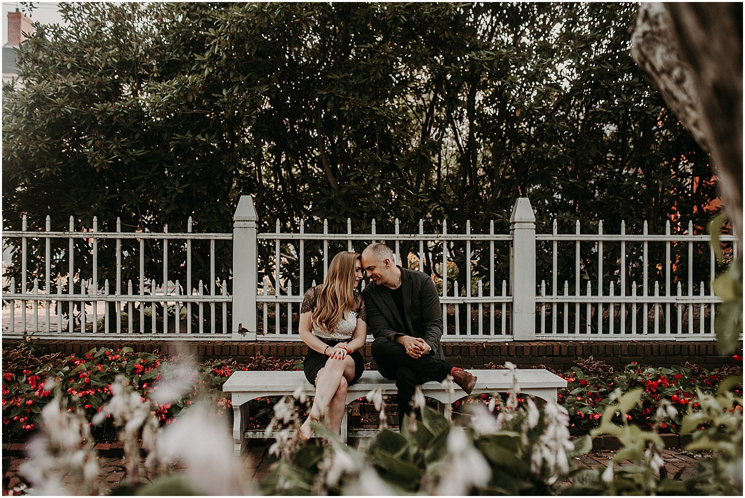 couple in front of a white fence cuddling at their Portsmouth Engagement Photography