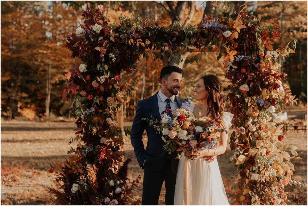 Wedding couple in front of floral decorated arch
