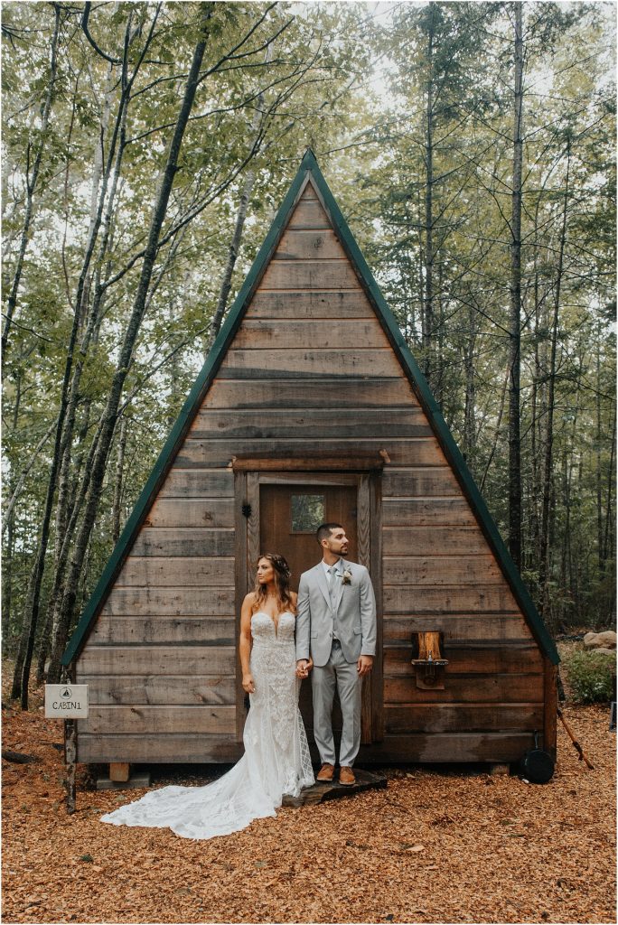 bride and groom in front of A frame cabin
